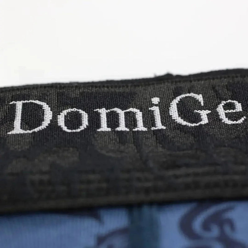 Close-up of DomiGe brand logo precision-woven into bamboo fiber fabric using CAD weaving technology on cobalt blue boxer briefs	