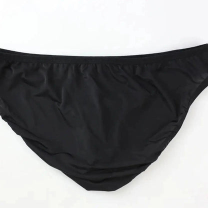 DomiGe elephant cock sock briefs in black — flat lay side view showing contoured pouch and waistband	