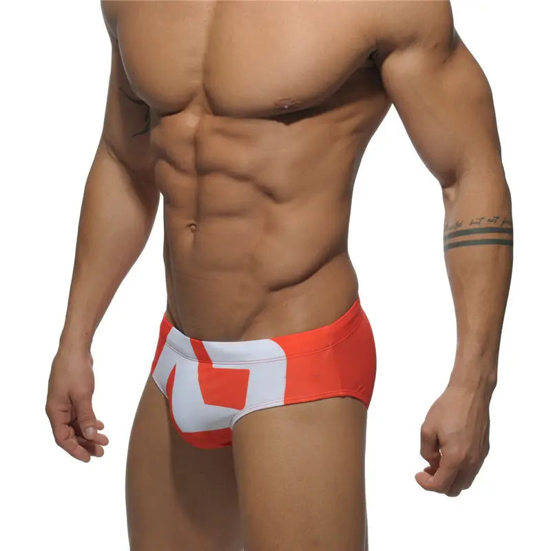 DomiGe fashion swim briefs in orange — model side view	