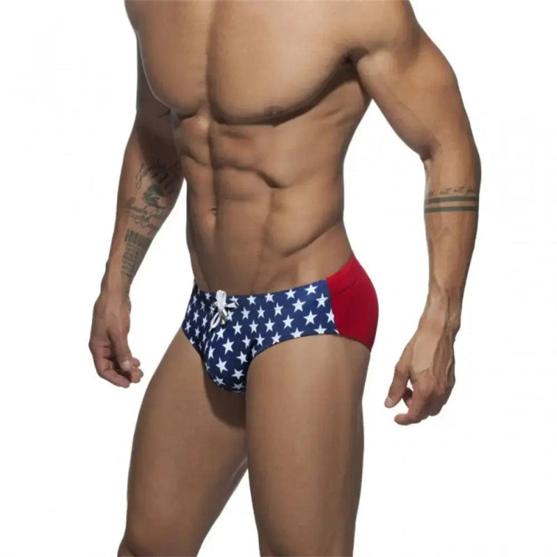 DomiGe flag print swim briefs in blue — model side view	
