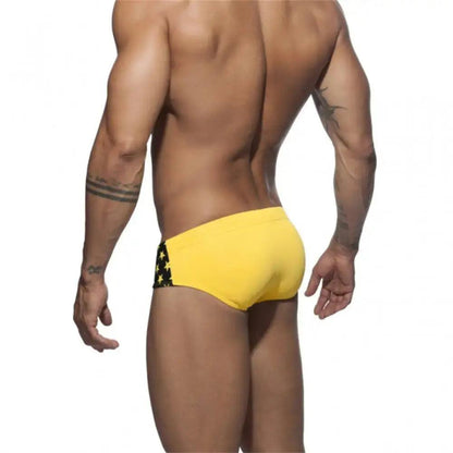 DomiGe flag print swim briefs in yellow — model rear view	