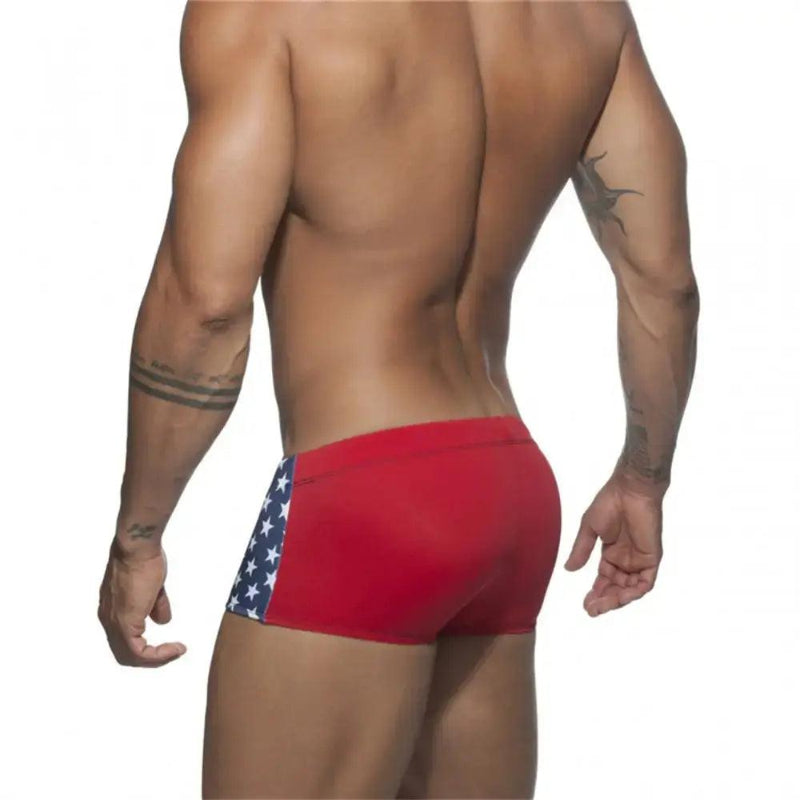 DomiGe men's flag print swim trunks in blue — model rear view showing square leg cut	