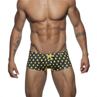 DomiGe men's flag print swim trunks in yellow — model front view showing vibrant colorblock print	