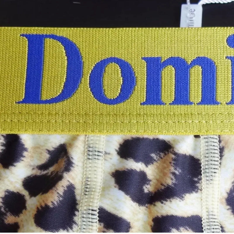 Close-up of DomiGe yellow leopard print boxer shorts — four-needle six-thread precision stitching detail at front panel	