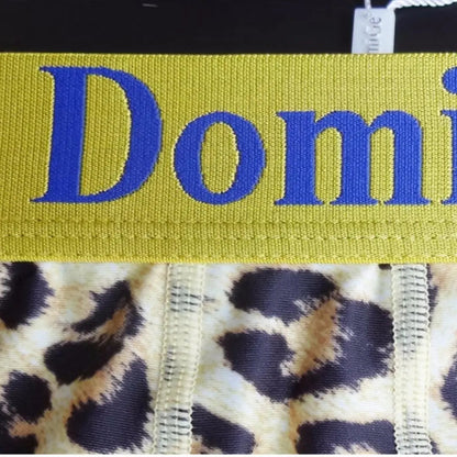 Close-up of DomiGe yellow leopard print boxer shorts — four-needle six-thread precision stitching detail at front panel	